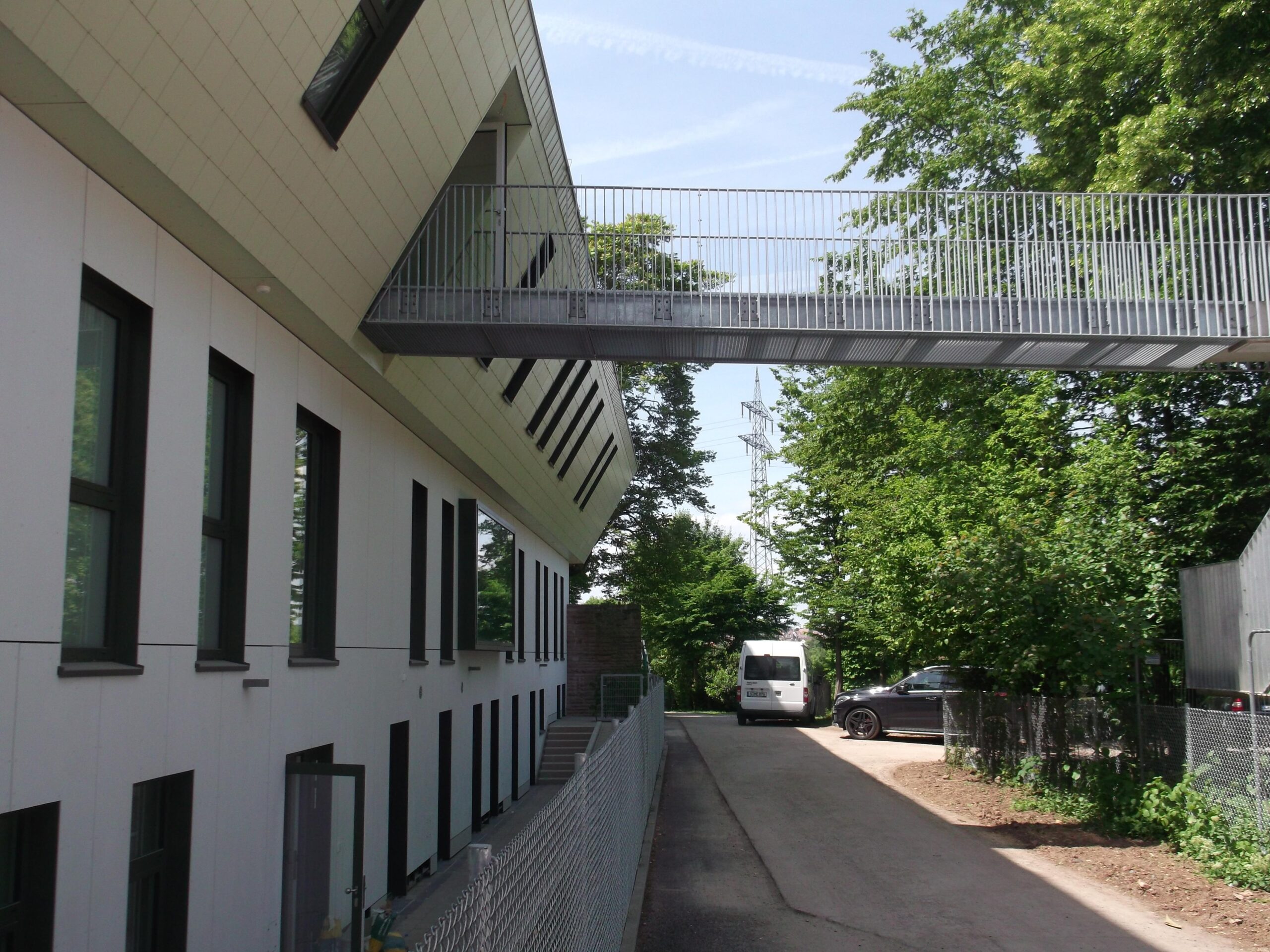 Fertiggestellte Kindertagesstätte — Blick zwischen den beiden Gebäudevolumen mit Steg und gefaltetem Metalldach